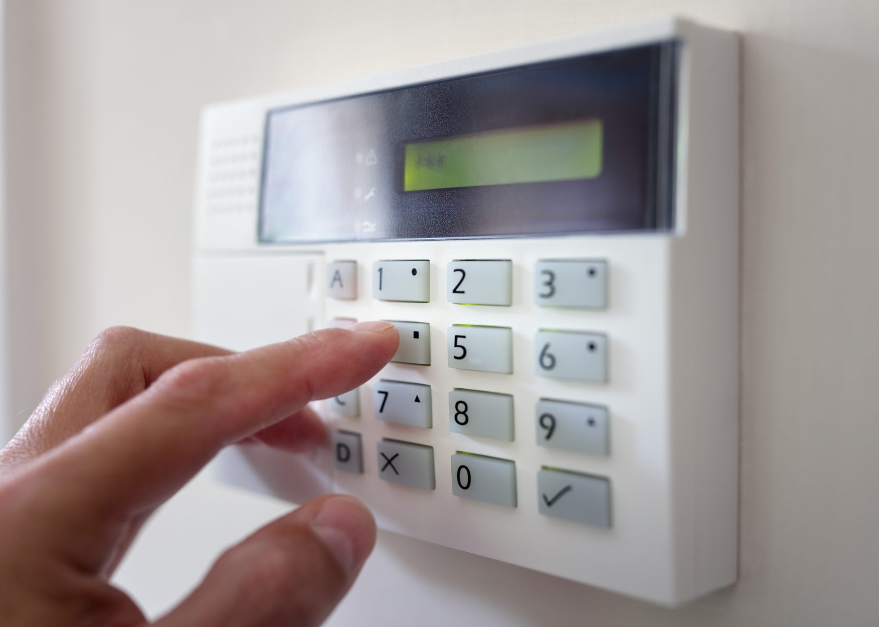 Hand entering a code on an alarm keypad